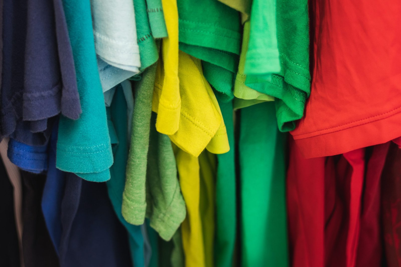 a bunch of colorful shirts hanging on a rack